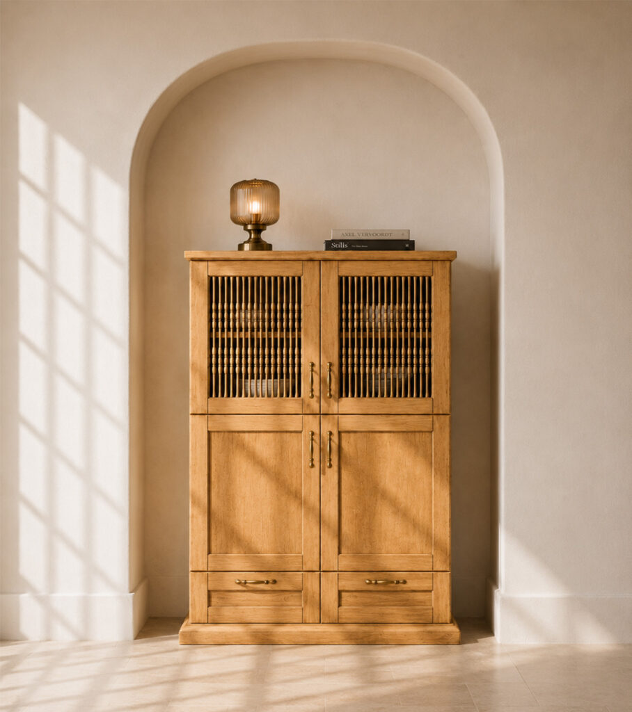 Cabinet placed in a shallow ivory plaster archway with a light stone floor, striped sunlight, a tinted-glass lamp and books on top.
